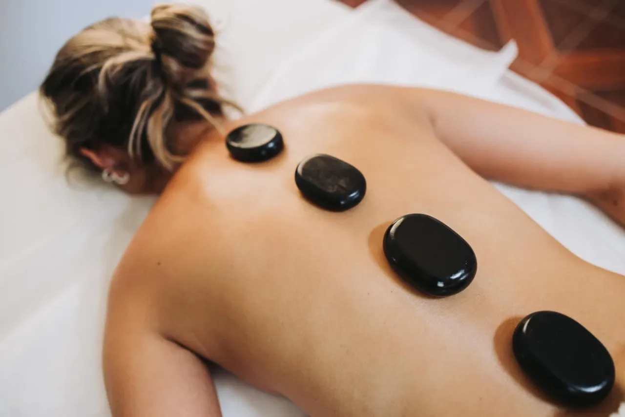 Masaż gorącymi kamieniami – rozgrzane kamienie ułożone na plecach klientki w Beauty Essence