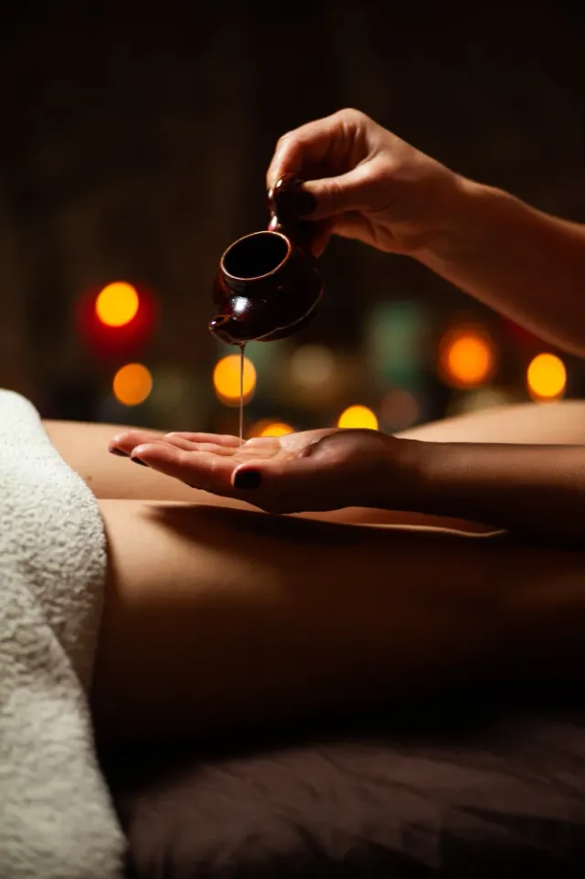 Masaż olejkami aromatycznymi – masażystka nalewa olejek na dłoń przed zabiegiem Beauty Essence