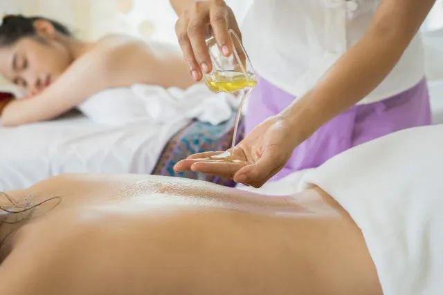 Masaż olejkami aromatycznymi – terapeutka nalewa olejek przed zabiegiem w Beauty Essence